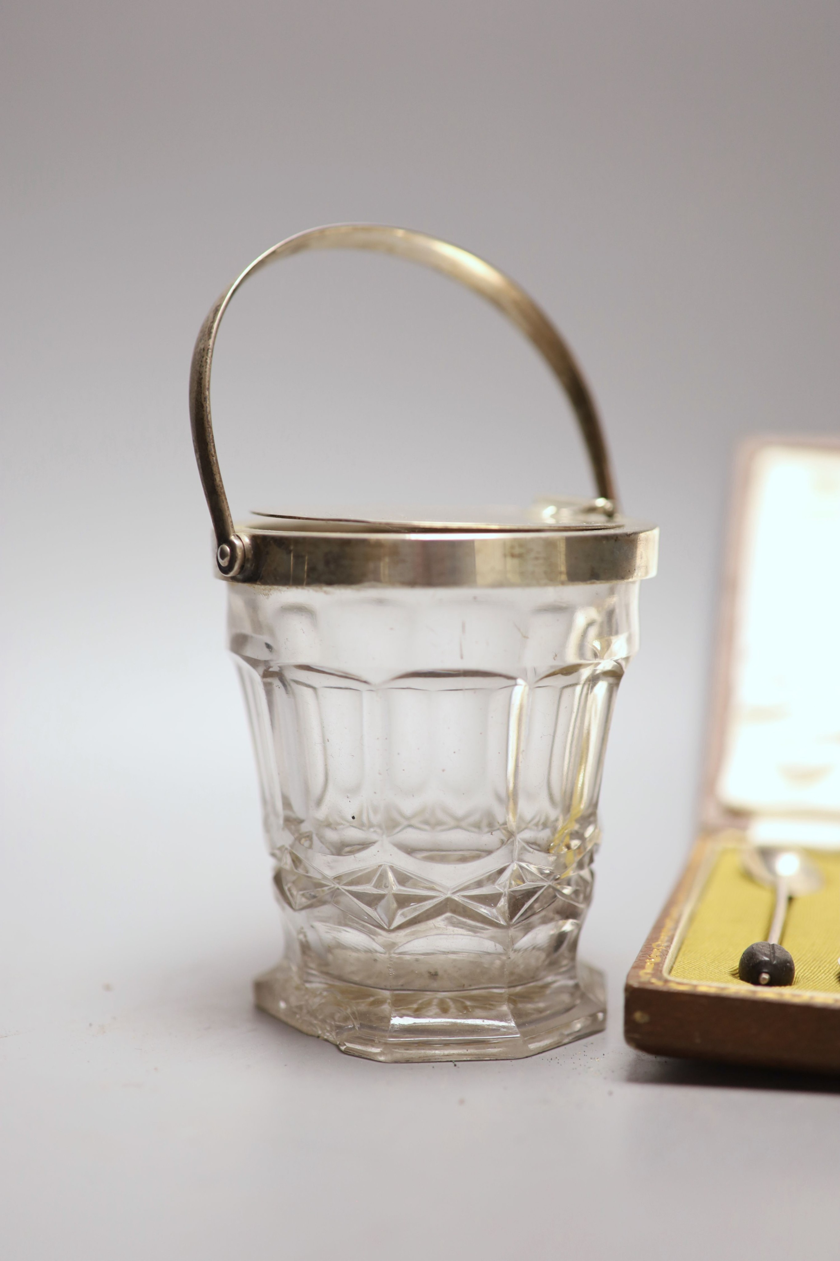 A cased set of six silver bean end coffee spoons and a George V silver mounted glass patent action sugar vase, (chipped foot).